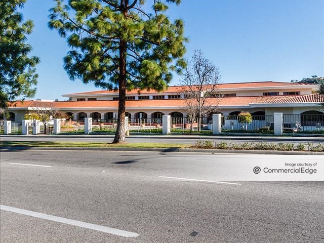 Exterior shot of 4500 Park Granada, a three-story office building with white and beige facade and a brown roof. The low-rise is surrounded by greenery.