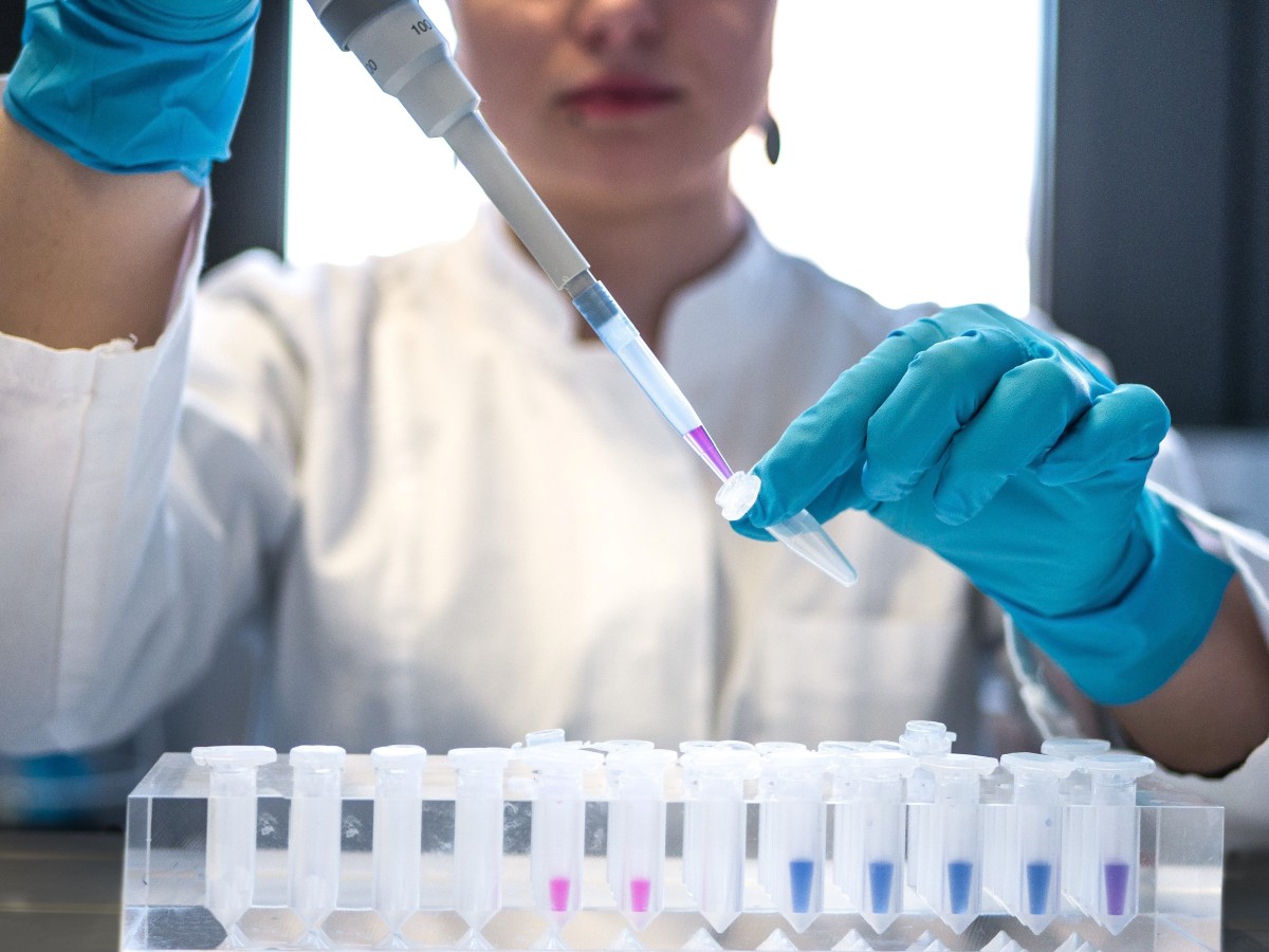 Scientist pipetting colored chemicals into a tube.