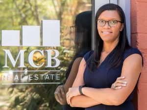 Gina Baker Chambers and window with MCB Real Estate logo