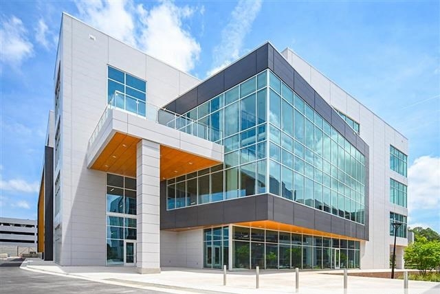 A modern building featuring sleek glass walls, reflecting its contemporary architectural design against a clear sky.