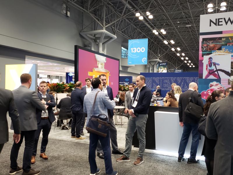 People standing in and talking in front of a booth at an exhibition hall and waiting for meetings