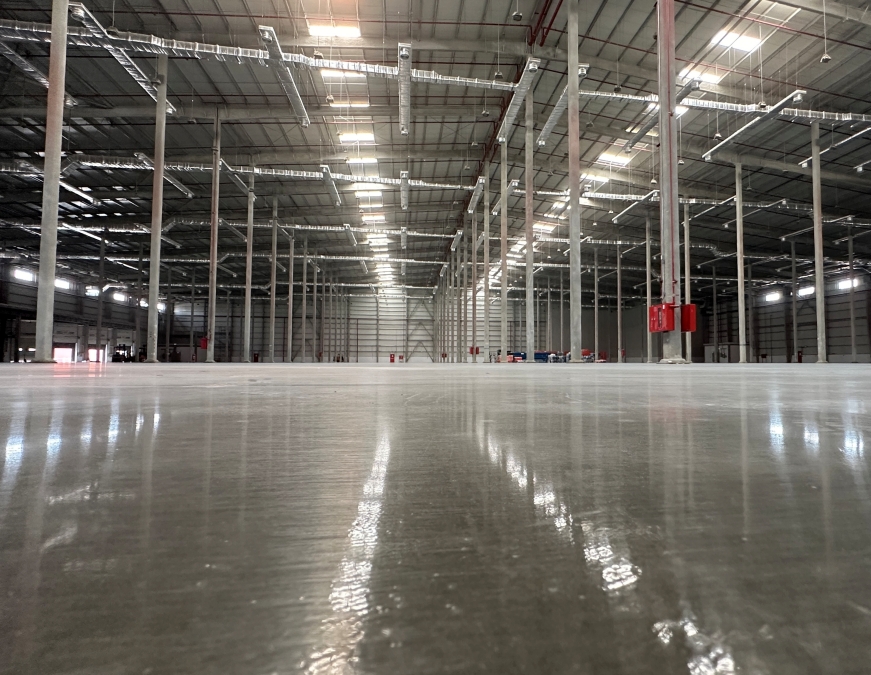 A spacious warehouse featuring a vast floor area and numerous large windows allowing ample natural light.