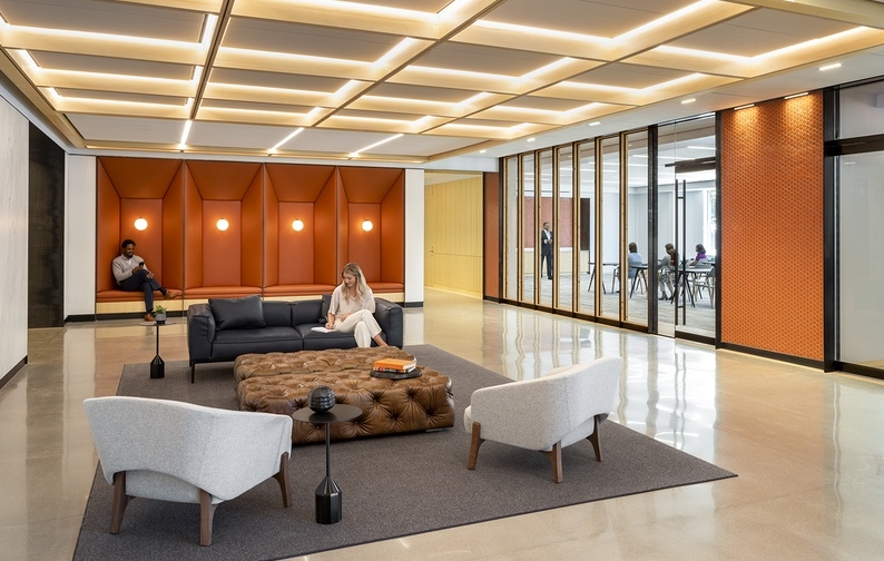 An office lobby showcasing sleek white furniture and bright orange accents, designed for a contemporary and inviting space.