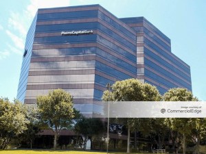 Exterior shot of Fountainhead Tower, the 10-story office building in San Antonio, Texas. The mid-rise is surrounded by trees and has a glass façade.