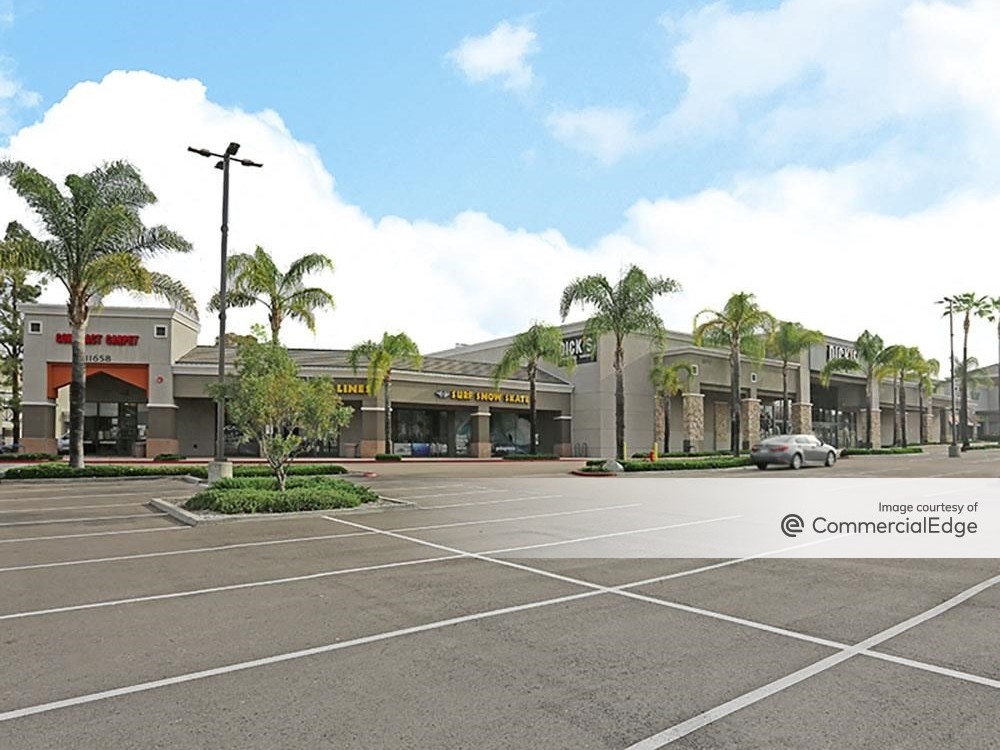 Exterior shot of 11602 Carmel Mountain Road, a retail center in San Diego. The one-story, brown-façade shopping mall has a parking lot and is surrounded by palm trees.