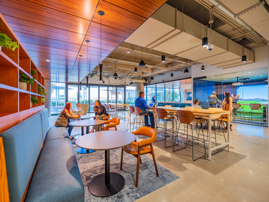 Interior shot of one of the common area lounges at Granite Park Six, with tables and cushioned chairs and sofas.