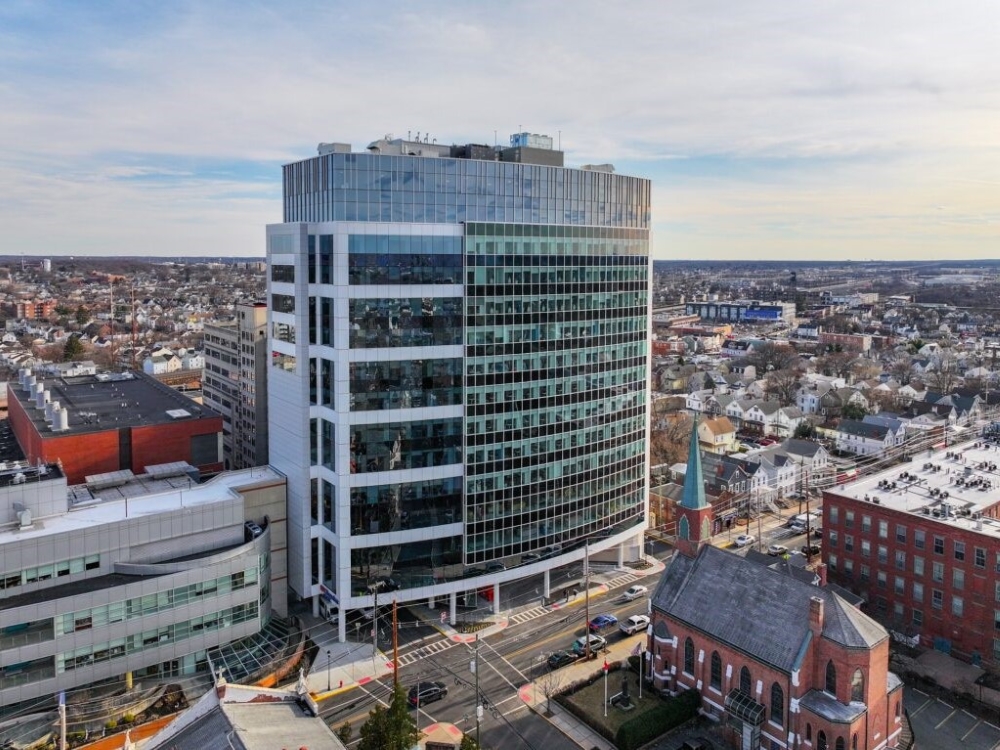 Exterior shot of Robert Wood Johnson University Hospital Ambulatory Medical Pavilion, a 15-story building with white and glass façade. The building is surrounded by lower properties.