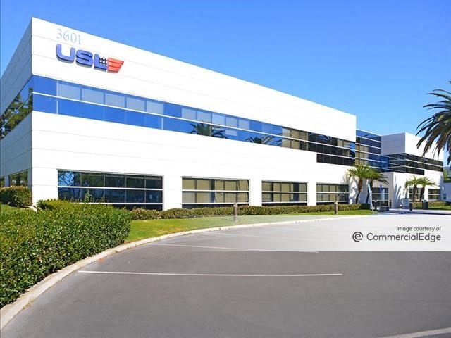 Exterior shot of one of the buildings within the SoCo Harbor campus. The facility rises two stories and has a white façade.